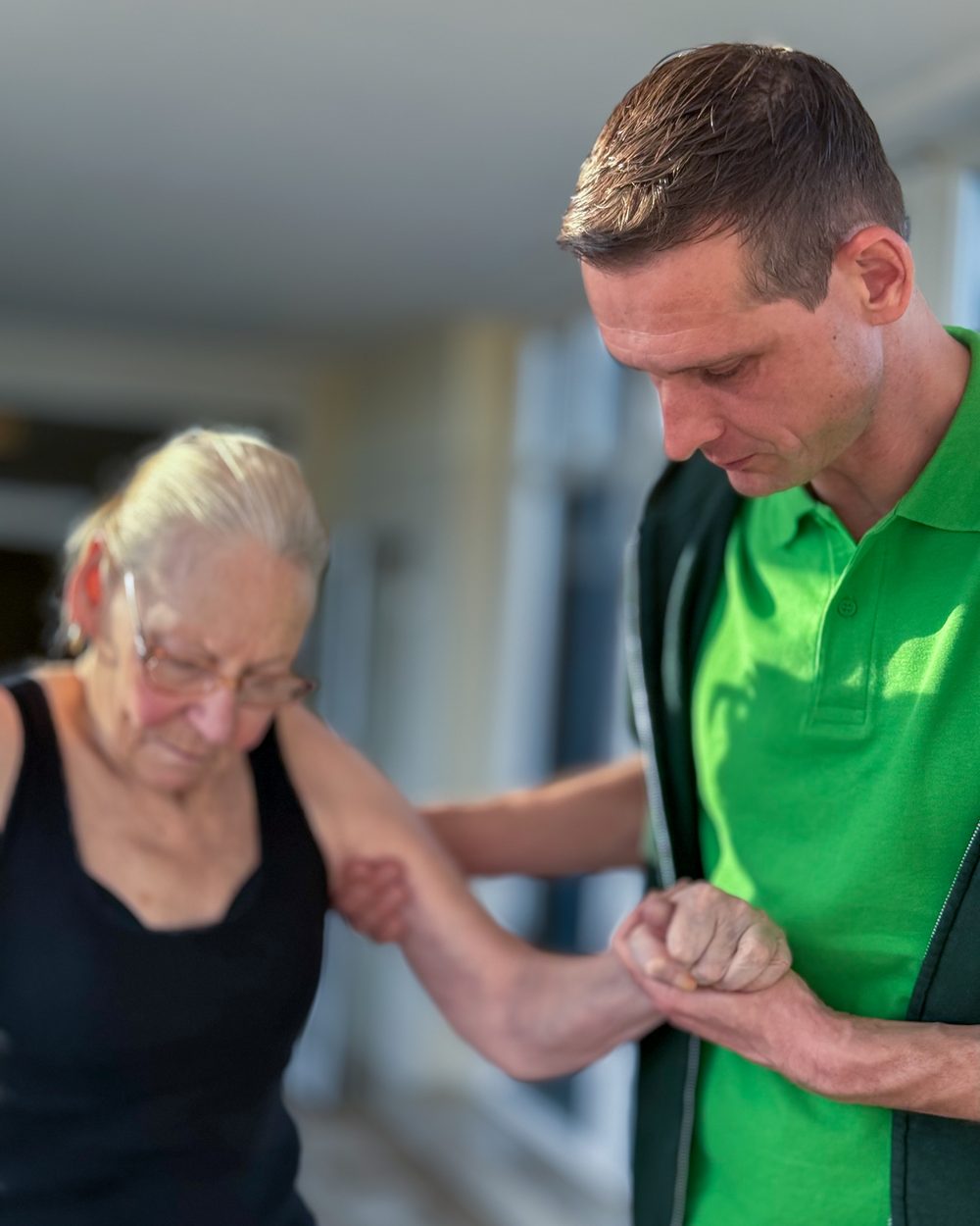 Physiotherapeut unterstützt eine Seniorin beim Gehtraining im PHYSIOPARK Berlin